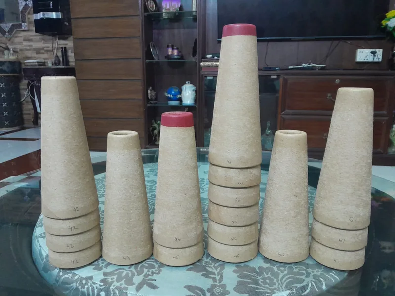 Paper yarn cones and tube cores with assorted rim colors arranged in a studio display